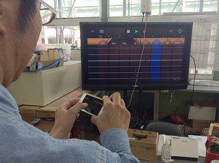 iPod Touch で GarageBand のスマートギターを操作する様子が地デジテレビに映し出されています。