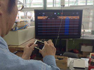 iPod Touch で GarageBand のスマートギターを操作する様子が地デジテレビに映し出されています。